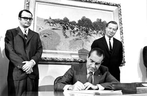 In this photograph from December 31, 1970, President Nixon signs the Clean Air Act as the first Environmental Protection Agency Administrator William Ruckelshaus and the Council on Environmental Quality Chairman Russell Train look on.