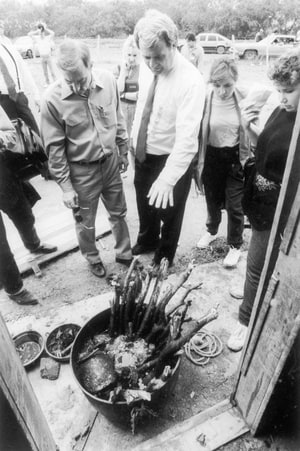 Texas Attorney General Jim Mattox (white shirt, center) views cauldron of bones found at ranch where 12 bodies were found buried including the body of U.S. college student Mark Kilroy.