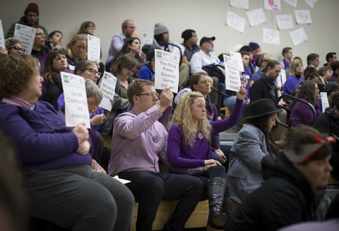 Dave and Hannah Edwards (in center holding hands), the parents of a gender nonconforming child at Nova Classical Academy, sat with signs in silent protest during a talk by Autumn Leva the Minnesota Family Council called Title IX and Gender Identity on Tuesday, January 12, 2015, in St. Paul, Minn.