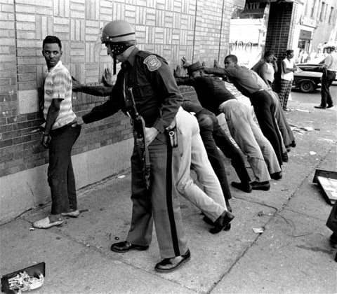 In this July 24, 1967 file photo, a Michigan State police officer searches a youth on Detroit's 12th Street where looting was still in progress after the previous day's rioting. The July 23, 1967 raid of an illegal after-hour’s club, though, was just the spark. Many in the community blamed frustrations blacks felt toward the mostly white police, and city policies that pushed families into aging and over-crowded neighborhoods.