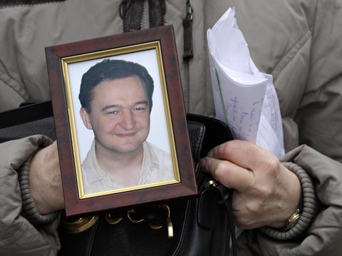 This is a Monday, Nov. 30, 2009 file photo showing a portrait of lawyer Sergei Magnitsky who died in jail, as it is held by his mother Nataliya Magnitskaya, as she speaks during an exclusive interview with the AP in Moscow. Russian investigators said Tuesday, Aug. 2, 2011, they reopened a criminal probe against the dead lawyer who claimed to have uncovered a massive tax fraud by corrupt police officers.