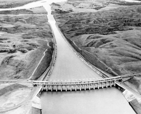 This Sept. 18, 1946 aerial view taken from a U.S. Army airplane flying over Fort Peck Lake, near Glasgow, Mont. shows operational tests of the mile-long concrete lined spillway of the Fort Peck Dam, the first of the U.S. Army Corps of Engineers' dams to be completed in the Missouri River basin. In the foreground is a structure, 800 feet wide and 86 high, which supports 16 floodgates. A $25 million, five-year study was authorized by Congress to determine whether changes need to be made in the 1944 law that sets eight purposes for the dams, reservoirs and lower free-flowing river: flood control, navigation, hydropower, irrigation, water supply, recreation, water quality, and fish and wildlife.
