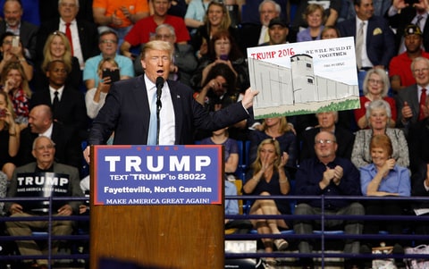 U.S. Republican presidential candidate Donald Trump holds a sign supporting his plan to build a wall between the United States and Mexico that he borrowed from a member of the audience at his campaign rally in Fayetteville, North Carolina March 9, 2016. Trump was interrupted repeatedly by demonstrators during his rally.