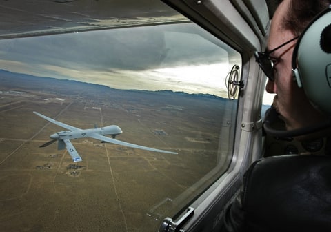 lot Mark Bernhardt keeps an eye a Predator unmanned drone from his chase plane as they fly over Victorville, CA, on January 9, 2010.