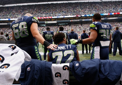 Center Justin Britt #68 of the Seattle Seahawks, left, and running back Thomas Rawls #34, right, join defensive end Michael Bennett #72 on the bench during the national anthem before the game against the San Francisco 49ers at CenturyLink Field on September 17, 2017 in Seattle, Washington.