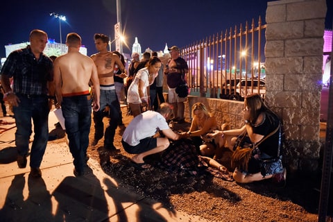 People tend to the wounded outside the Route 91 Harvest Country music festival grounds after an apparent shooting on October 1, 2017 in Las Vegas, Nevada. There are reports of an active shooter around the Mandalay Bay Resort and Casino.