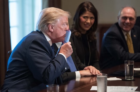 US President Donald Trump kisses a sample of the proposed new tax form as he meets with House Republican leaders and Republican members of the House Ways and Means Committee at the White House in Washington, DC, on November 2, 2017.