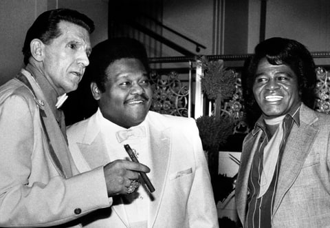 Jerry Lee Lewis, Fats Domino, and James Brown stand together at the Waldorf-Astoria Hotel. They were three of the first inductees into the Rock and Roll Hall of Fame.