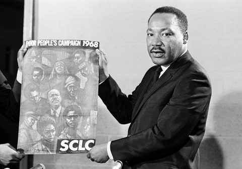 Civil rights leader Rev. Dr. Martin Luther King, Jr., president of the Southern Christian Baptist Leadership Conference (SCLC), displays the poster to be used during his Poor People's Campaign in the summer of 1968.