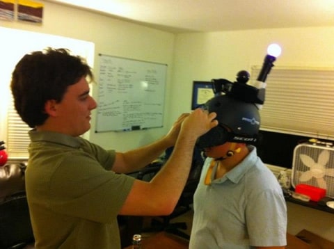Palmer Luckey places a prototype Oculus Rift Razer Hydra VR helmet onto a Survios founder's head
