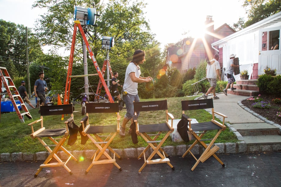 'Red Oaks' crew member takes a photo from the cast's chairs